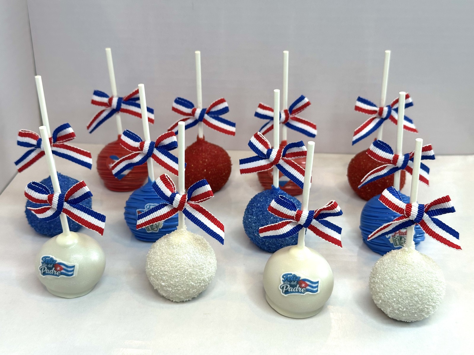 Cuba themed cake pops in red, white, and blue with decorative bows