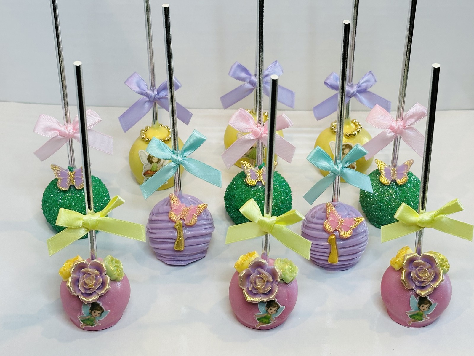 Elegant pastel fairy themed cake pops with floral details and satin bows