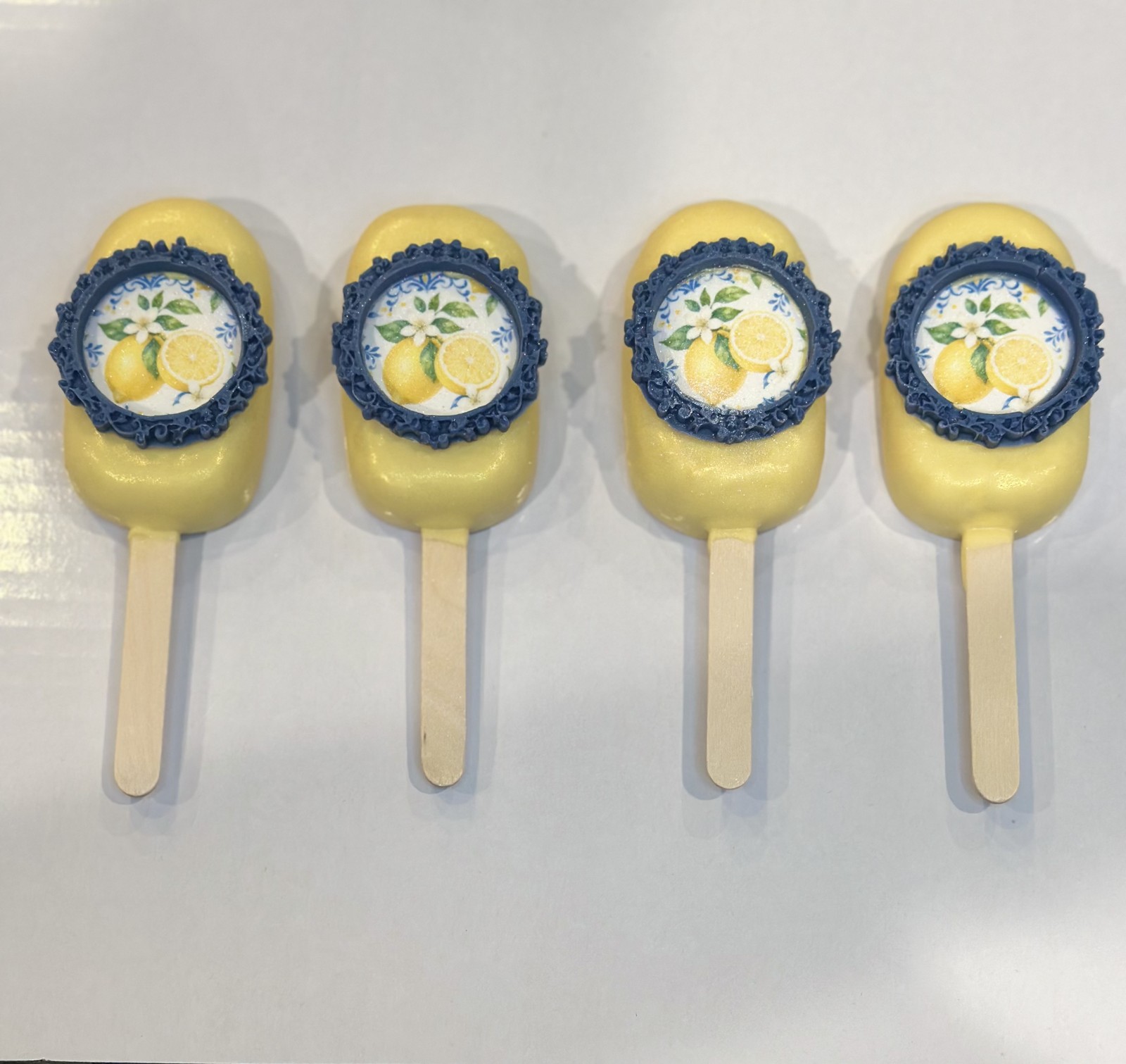 Yellow cakesicles with ornate navy frames and lemon artwork