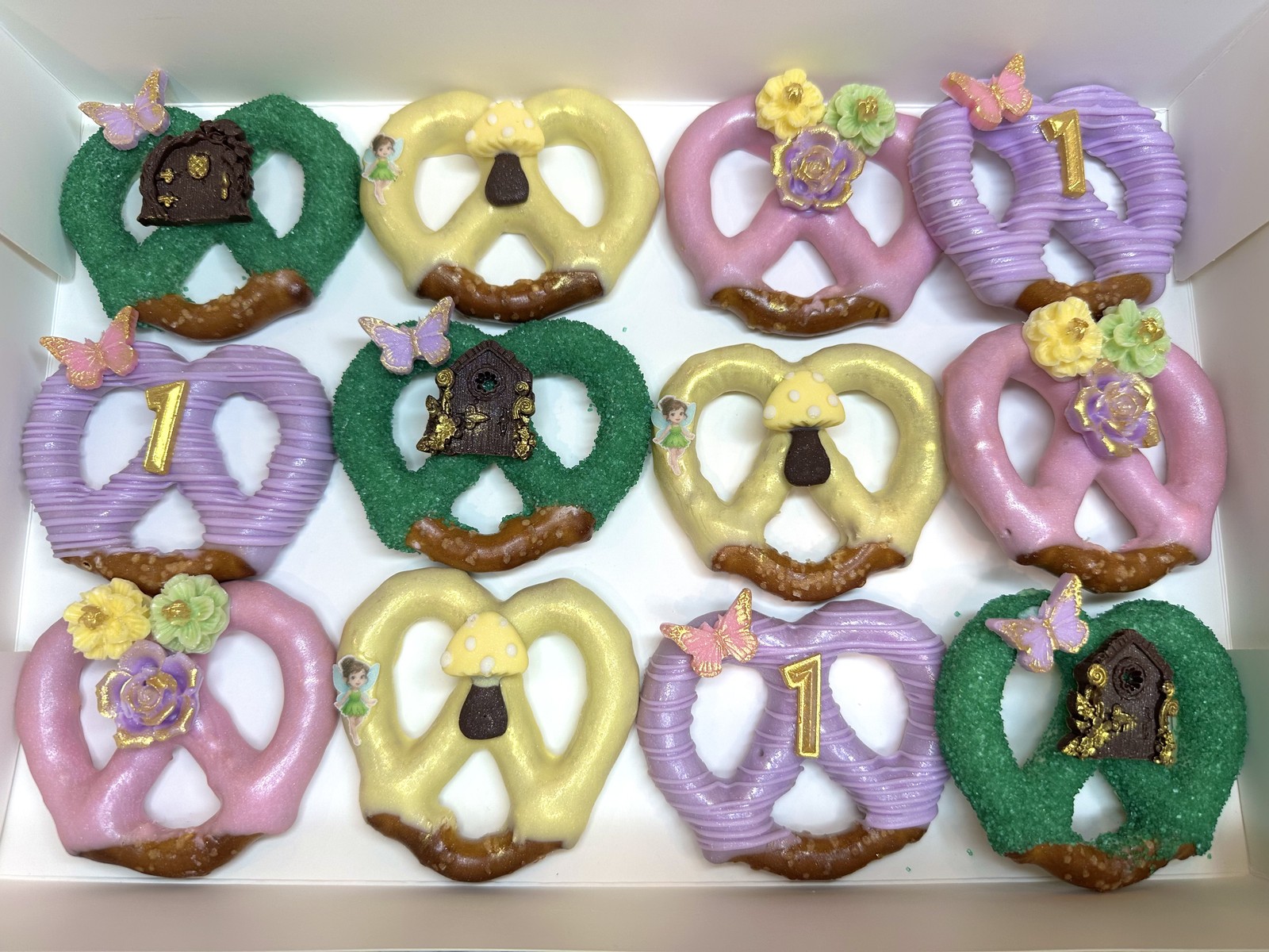 Elaborate pastel fairy first birthday chocolate covered pretzel twists with butterflies, flowers, mushrooms, and gold details