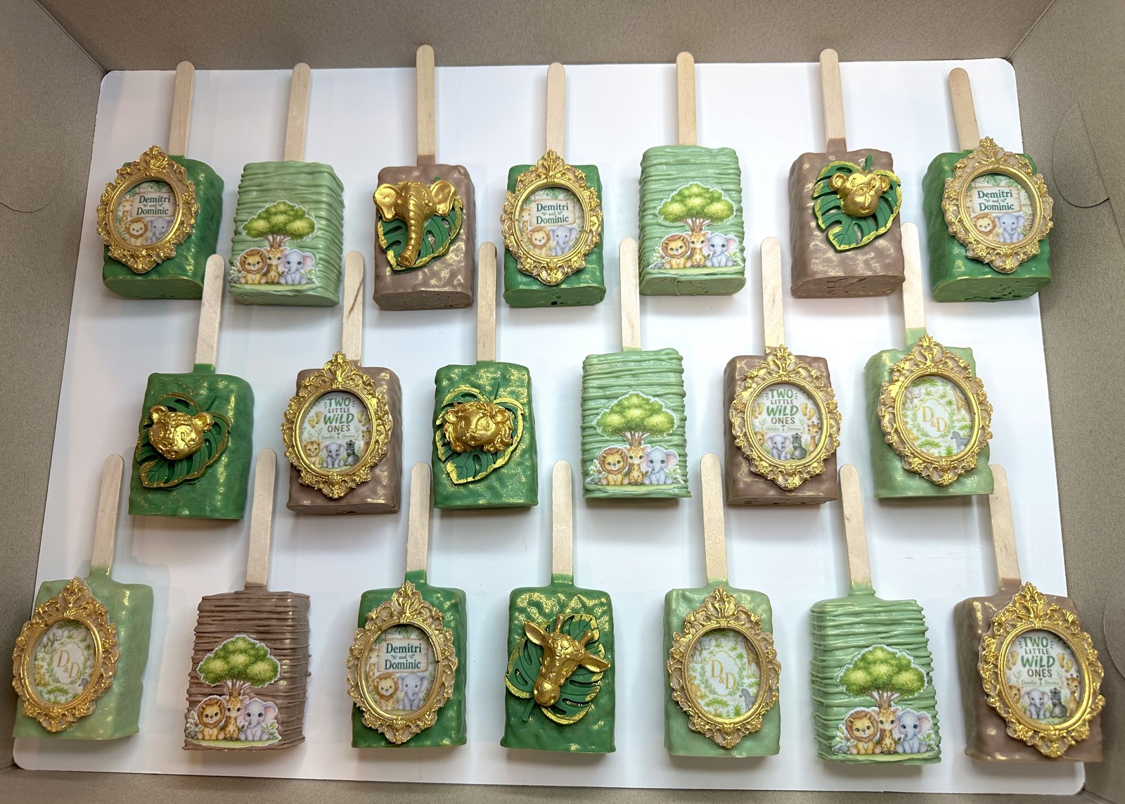 Elegant sage green, ivory, and gold Baby in Bloom chocolate covered Rice Krispie treat collection with ornate frames and satin bows