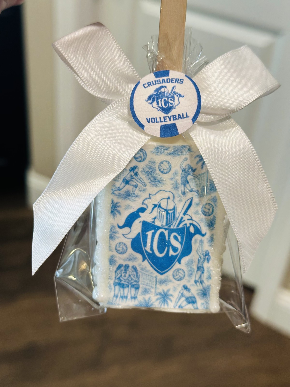 Individually wrapped white Crusaders volleyball chocolate covered Rice Krispie treat with blue framed Go Crusaders design and white bow