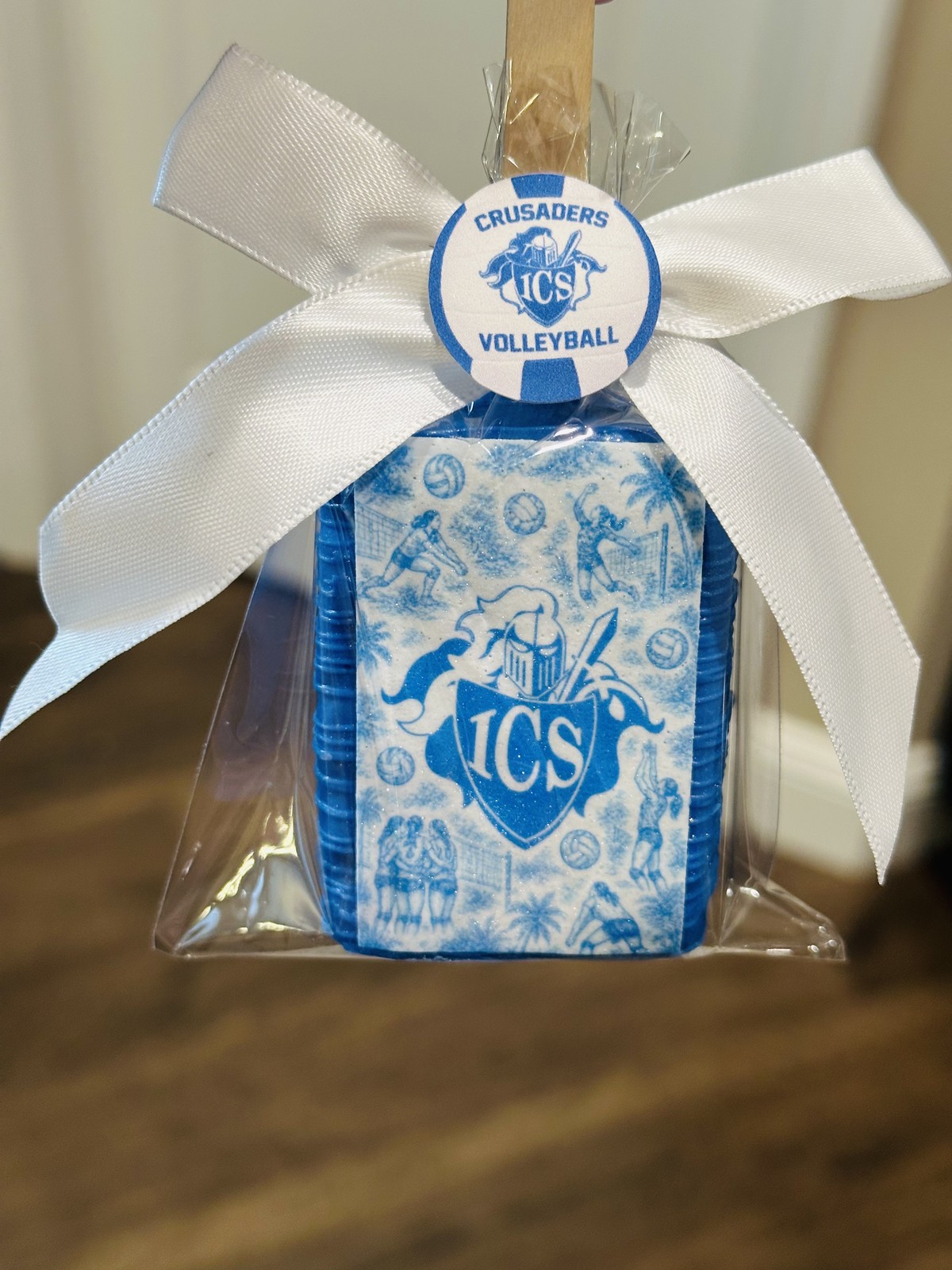 Individually wrapped white Crusaders volleyball chocolate covered Rice Krispie treat with blue sugar frame and white bow