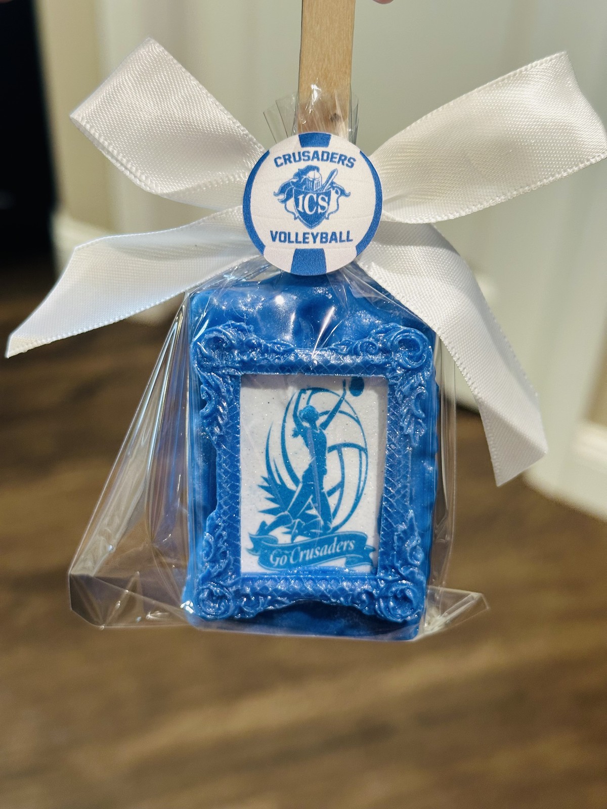 Individually wrapped blue Crusaders volleyball chocolate covered Rice Krispie treat with blue toile-style edible design and white bow