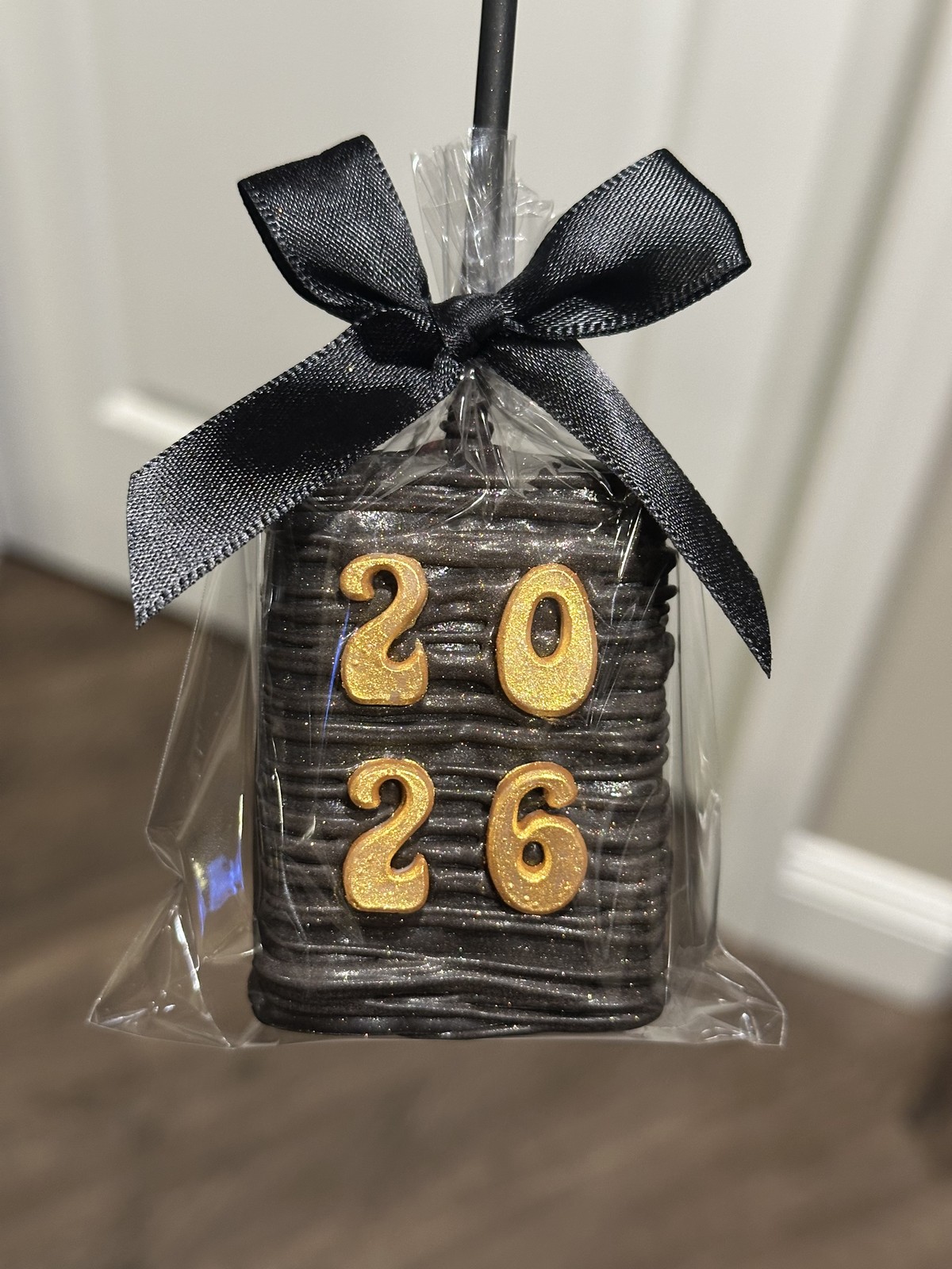 Individually wrapped black and gold graduation chocolate covered Rice Krispie treat with GRAD lettering and black bow