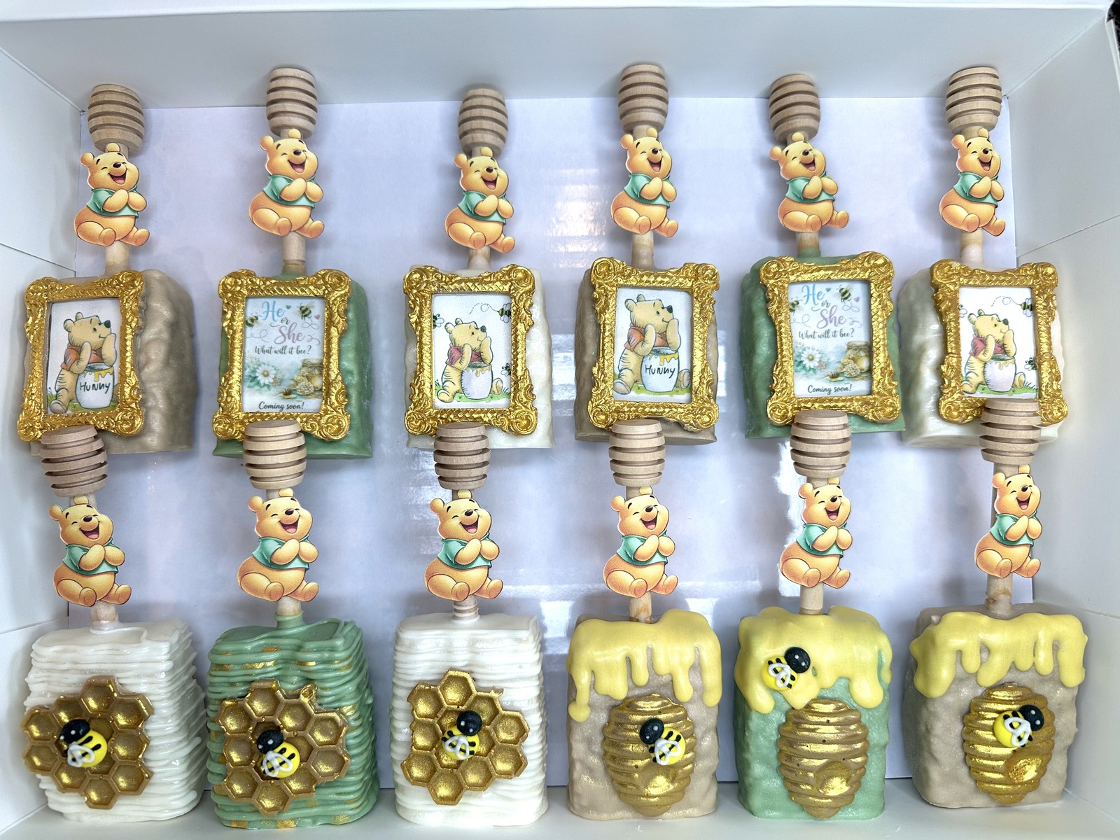 Luxury Winnie the Pooh baby shower chocolate covered Rice Krispie treat collection in soft pink, yellow, and gold with ornate portrait frames and honey details