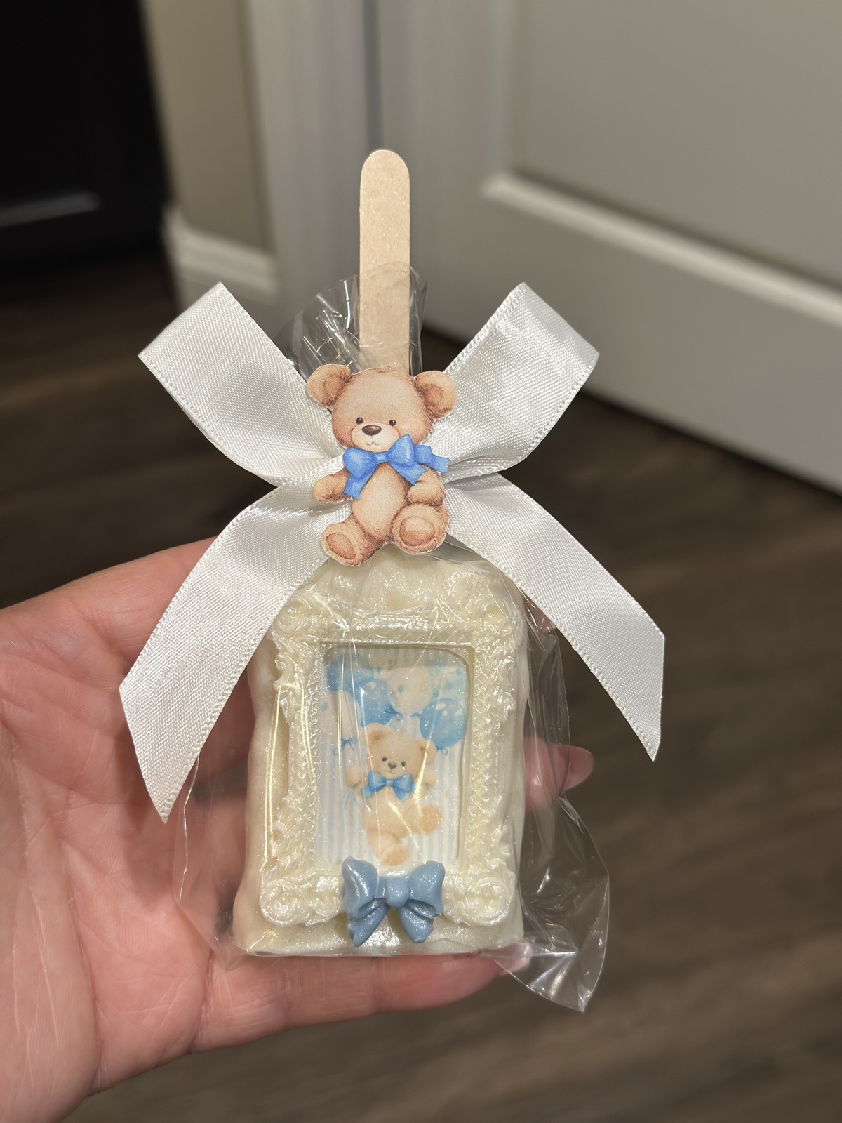 Individually wrapped blue and white teddy bear chocolate covered Rice Krispie treat with an ornate frame and satin bow