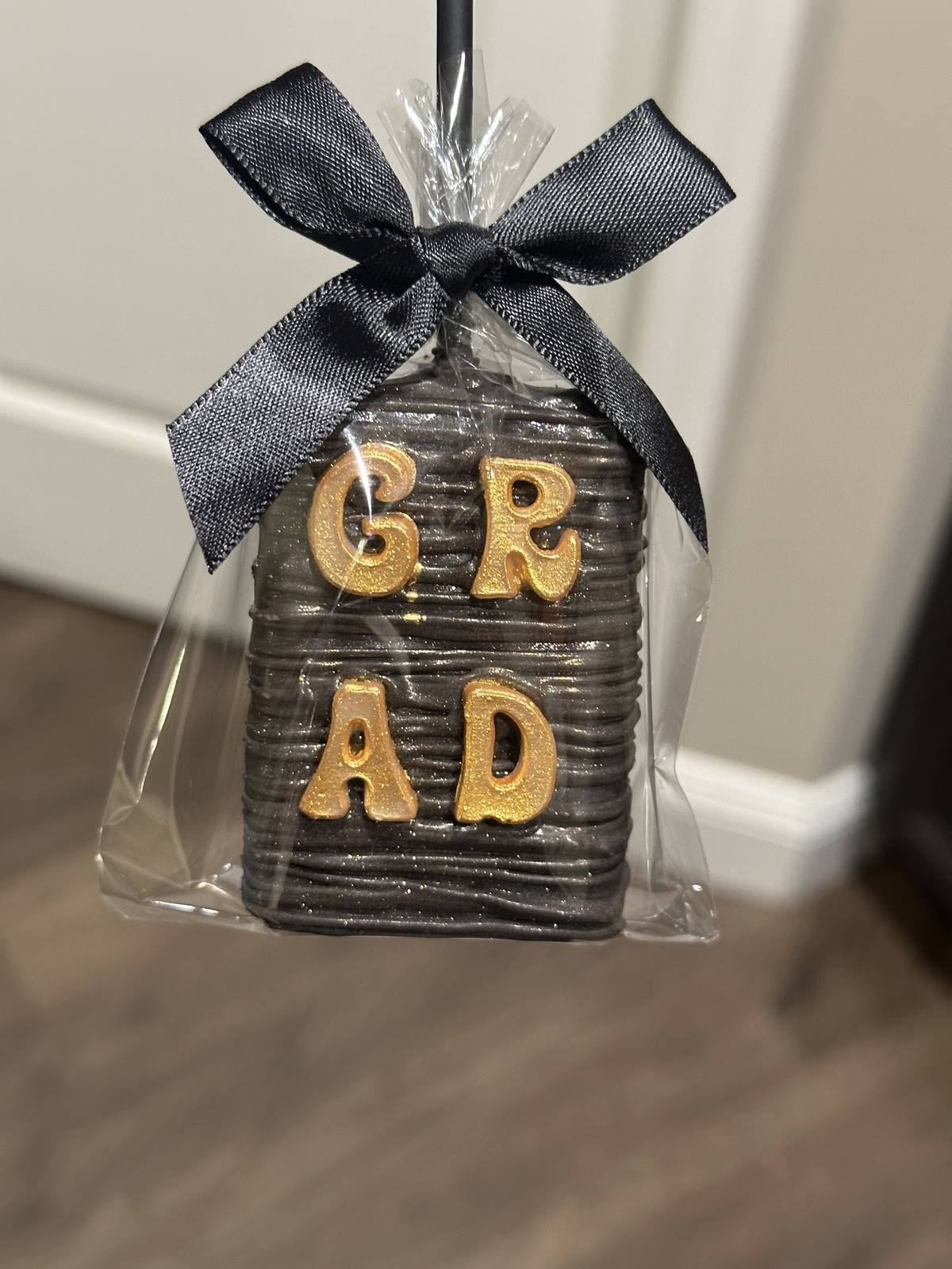 Individually wrapped red and gold graduation chocolate covered Rice Krispie treat with Graduate detail and black bow