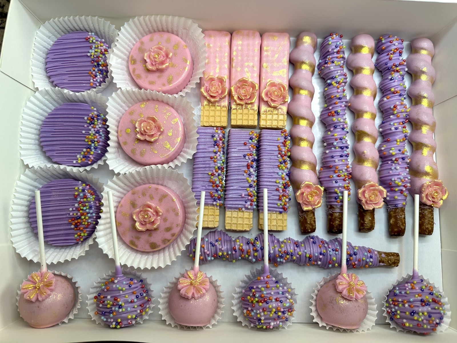 Luxury pink and purple coordinated dipped wafer collection with floral details, chocolate covered pretzels, Oreos, and cake pops